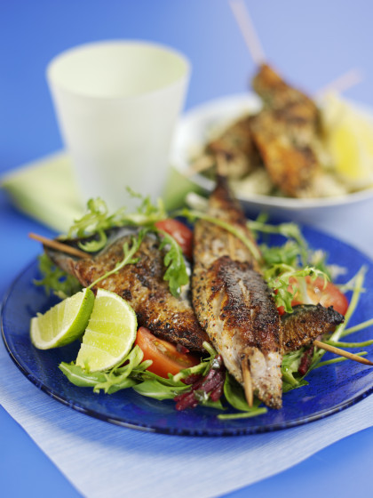 Grilled skewered fish on mixed salad