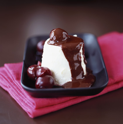 White chocolate cream with chocolate sauce and cherries