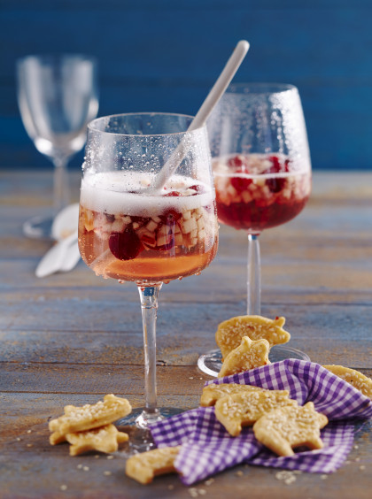 Fruity New Year's Eve punch with Prosecco and cranberries with spicy pig-shaped biscuits