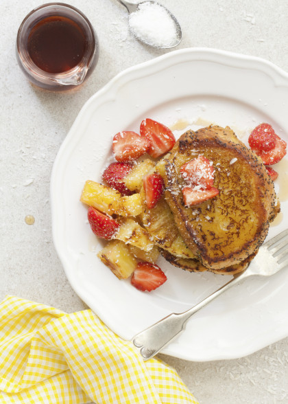 Vegan French toast with griddled pineapple, strawberries, coconut flakes and maple syrup