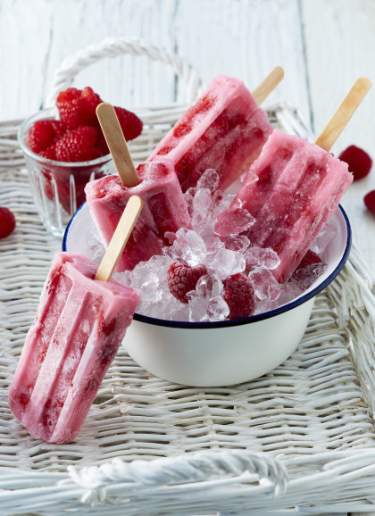Summer raspberry ice lollies on sticks with fresh raspberries on crushed ice