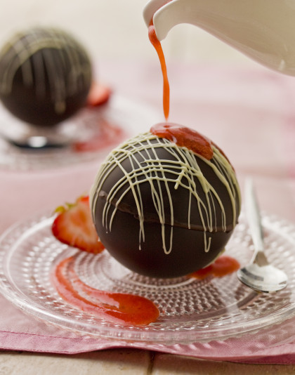 Chocolate spheres with melting hot strawberry sauce