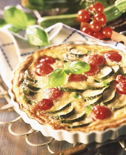 Courgette and tomato quiche garnished with basil