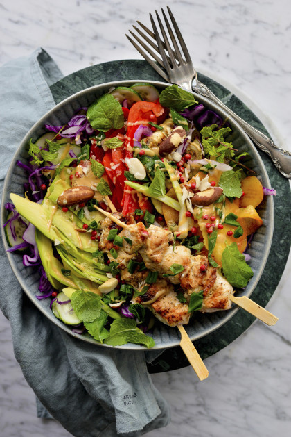 Healthy lunch with chicken skewers, avocado, nuts and mango